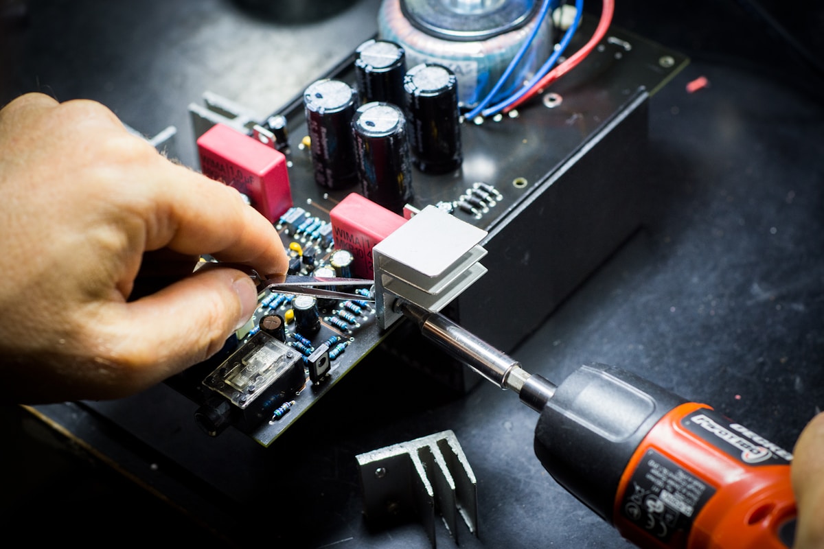 Hands soldering components onto PCB with soldering iron